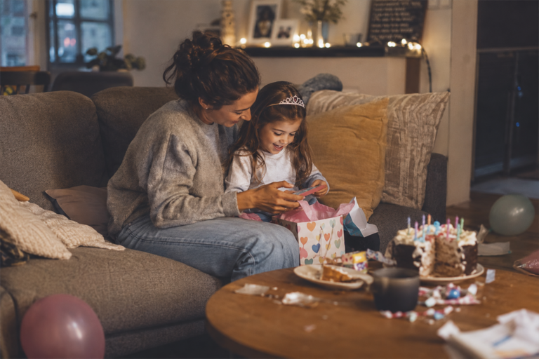 Mother and preschool child sharing a quiet birthday moment at home after the party