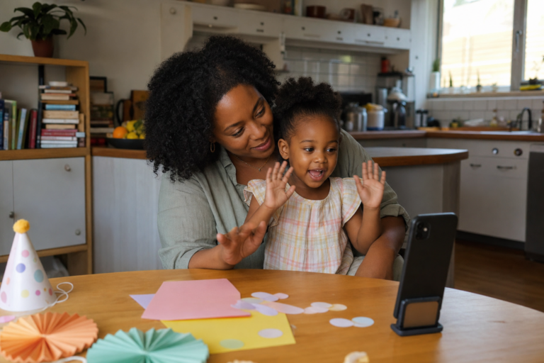 Black mother helping her young child record a birthday invitation video at the kitchen table