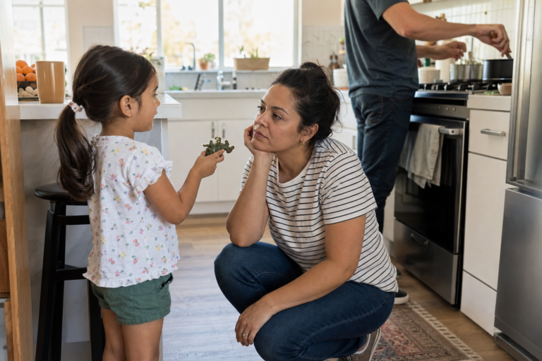 Latina mother listening to her young daughter in a family kitchen while dinner is being prepared