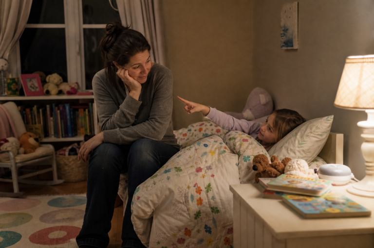 White mother sitting with her young child during bedtime in a cozy bedroom